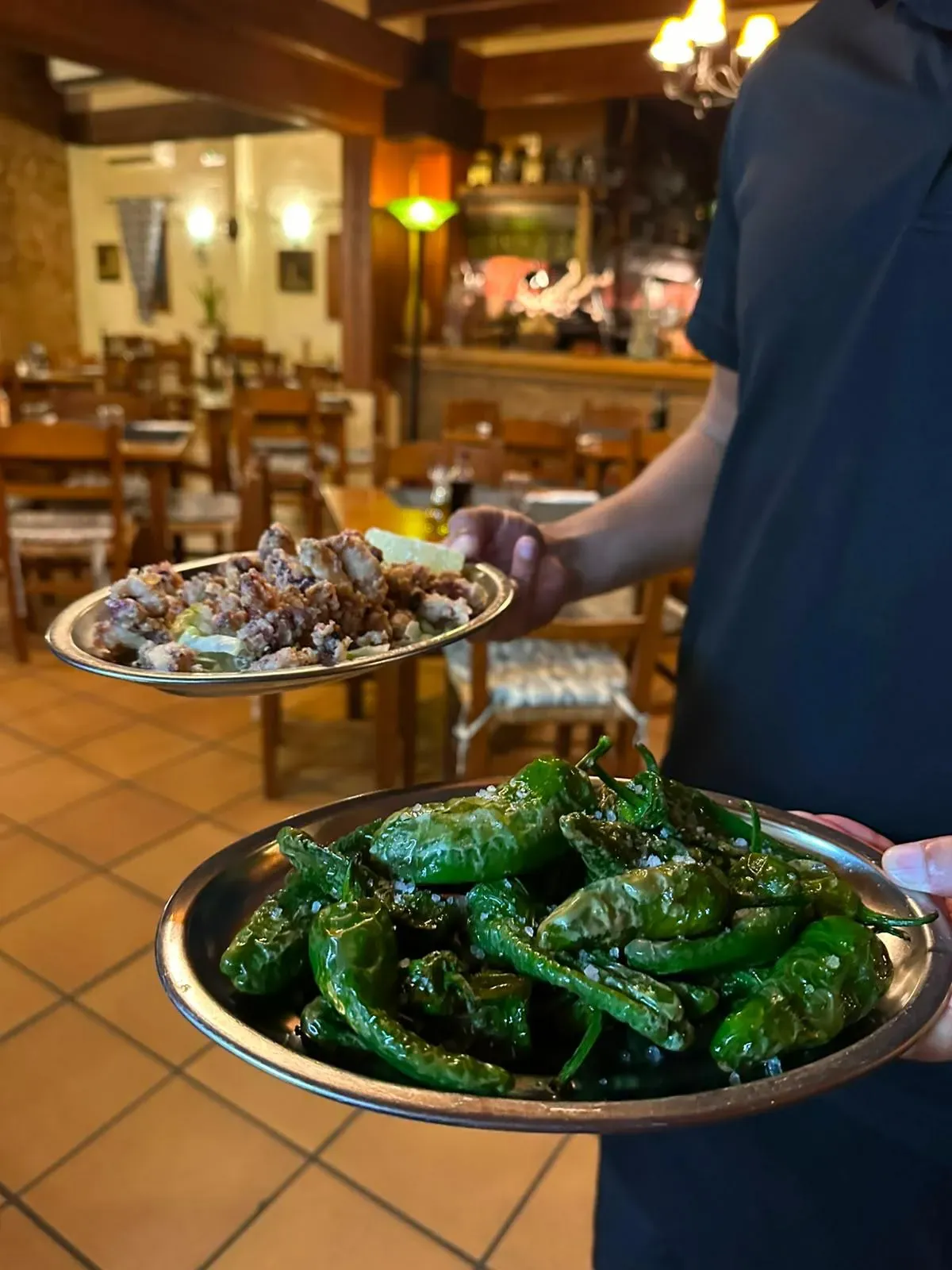 Waiter serving Padrón peppers in the dining room